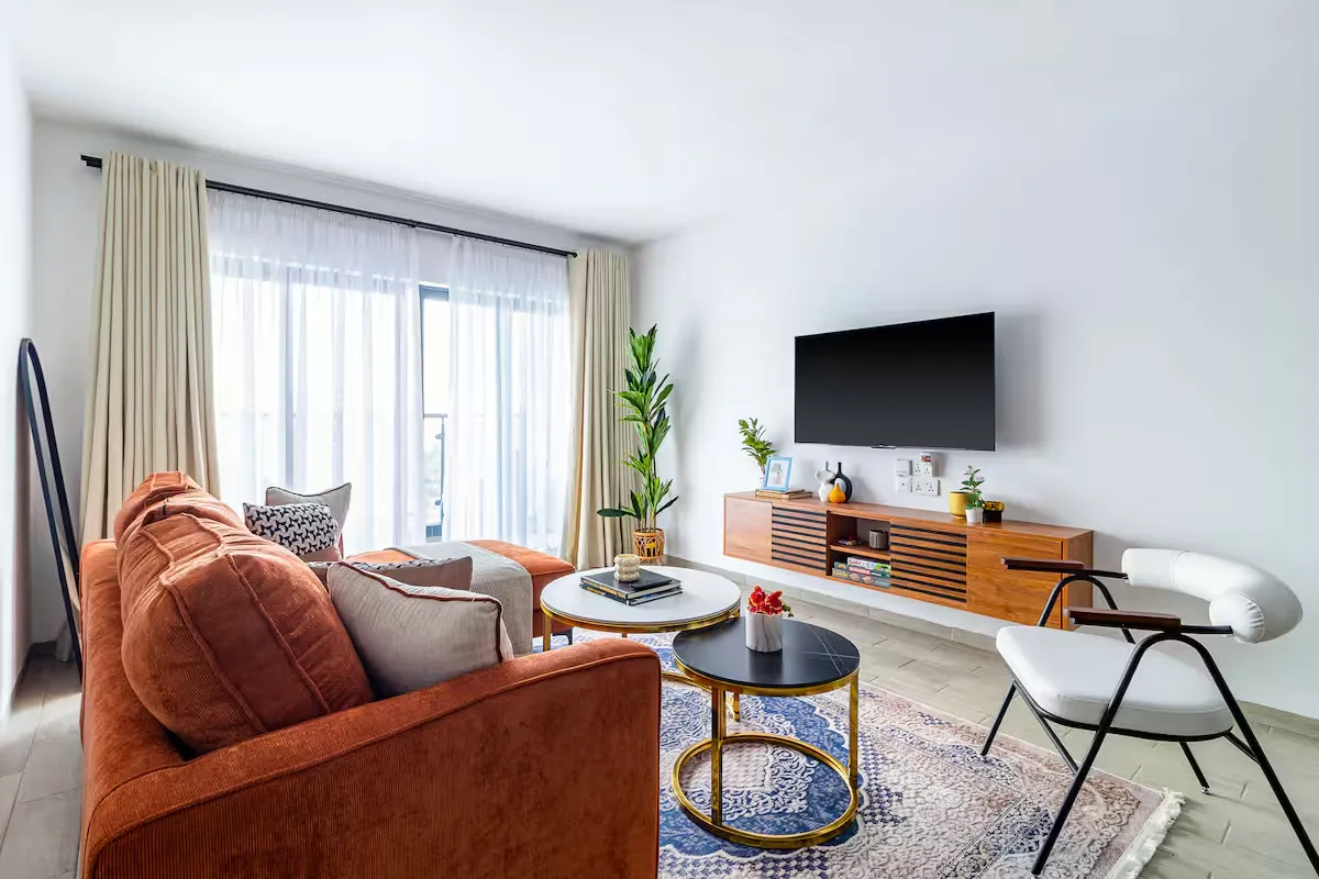 Bright living room with a rust-coloured sofa, patterned rug and round coffee tables